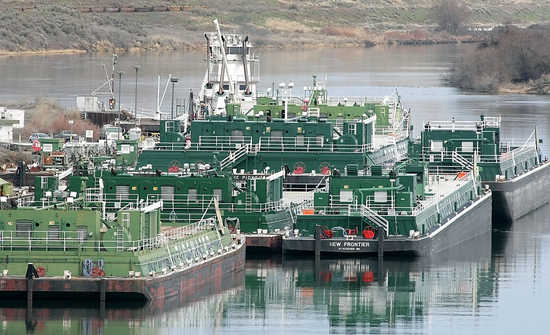 Empty barges and a tugboat sit idle on the Snake River near Pasco as the navigation locks on the Snake and Columbia Rivers have been shut down for maintenance and a replacement lock gate is being installed at Lower Monumental Dam.