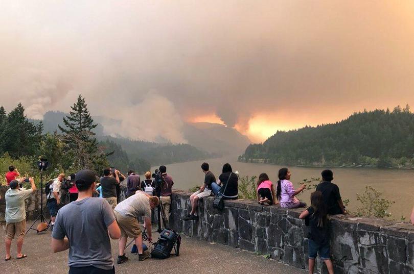 This Sept. 4, 2017, photo provided by Inciweb shows people at a viewpoint overlooking the Columbia River watching the Eagle Creek wildfire burning in the Columbia River Gorge east of Portland. (Inciweb / Associated Press)