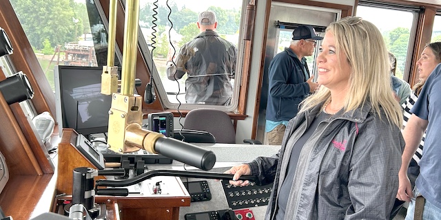Michelle Hennings, executive director of the Washington Association of Wheat Growers, drives a Shaver Transportation tugboat on the Willamette River as part of the collaborative tour between Pacific Northwest river stakeholders and members of the Upper Mississippi Waterway Association of the Columbia-Snake River system. (Trista Crossley/Washington Association of Wheat Growers)