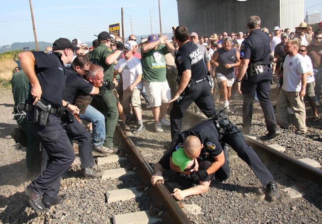 (Photo: Dawn Des Brisay/Flickr) Police attack ILWU pickets in Longview, Washington, September 7 as they block grain train to scab facility: 19 arrested. Despite federal injunciton, the next day 800 union supporters returned to seize the terminal. Ten thousand tons of grain were dumped, judge said he felt like a 'paper tiger'.