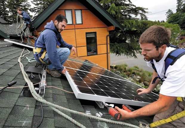 (Drew Perine photo) South Sound Solar employees from right Aaron Bonfield, Daniel Kuni and Brian Jones install one of 10 Itek solar panels on the roof of an Olympia home.