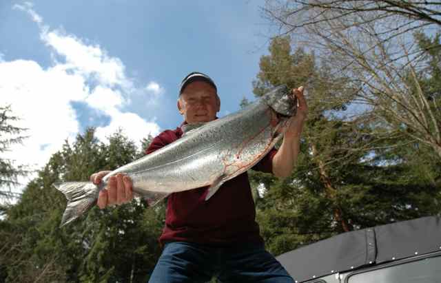 A female angler proudly displays her Steelhead catch.