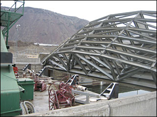 (ACOE) The two forward barges contacted the upstream lift gate as water rose in the navigation lock chamber. This contact lifted the upstream gate out of its tracks. This photo looks north across the locks to the north bank of the Columbia River.