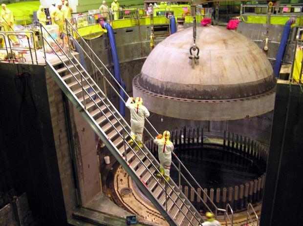 Energy Northwest workers watch as a crane lowers the reactor vessel head into place after a past refueling outage at the Columbia Generating Station north of Richland (Energy Northwest photo).