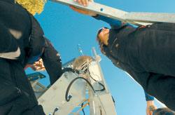 (Joshua Duplechian photo) Kevin Wade and Brandal Glenn stand on top of a cloud seeding tower in the McCall area to download information onto their personal computers for analysis at the office later in the day.