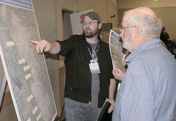 (Matthew Weaver photo) Odessa, Wash., farmer Brian Fink inspects plans to convey surface water to his and other farms affected by declining aquifer levels as fellow farmer Ronald Treat looks on Nov. 6 during the Columbia Basin Development League annual meeting in Moses Lake. Wash. Landowners will pay for delivery systems to their operations, but the league is still looking for $25 million to $30 million to finish work on the East Low Canal.