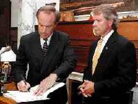 Gerry Melendez - Idaho Gov Dirk Kempthorne signs a four-state salmon recovery plan alongside Oregon Gov. John Kitzhaber during a news conference Tuesday at the Statehouse.  The regional plan, which offers general recommendations for the protection and restoration of salmon and steelhead in the Columbia River Basin, was agreed upon by the governors of Idaho, Montana, Oregon and Washington
