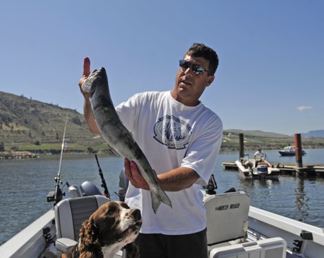 A fisherman and his dog dispay their catch.