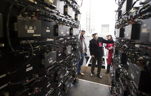 (Steven Lane photo) Powin Corporation Chief Technology Officer Virgil Beaston, left, shows the inside of a shipping container to Pacific Northwest National Laboratory employees Vish Viswanathan, center, and Chunlian Jin during a tour of a new battery storage unit at the BPA Ross Complex.