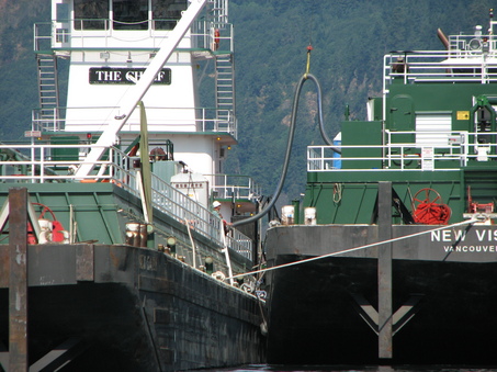 A hose is lowered into position earlier today between a grounded fuel barge on the Columbia River and a second, empty barge where the fuel was then offloaded. (Matthew Preusch/Oregonian photo)