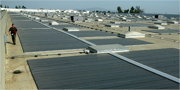 (Jill Connelly) A property manager examines the photovoltaic cells on the roof of a General Motors warehouse in Cucamonga, Calif. The cells have the capacity to generate as much as 1.5 million kilowatt hours of electricity a year