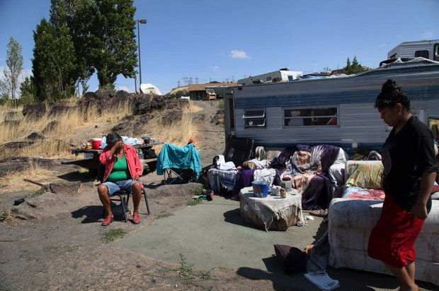 In this Aug. 22 photo at Lone Pine, resident Ranetta Spino, left, sits in front of the trailer home she shares with her relatives at the Native American fishing site on the Columbia River near The Dalles, (AP Photo/Gosia Wozniacka)
